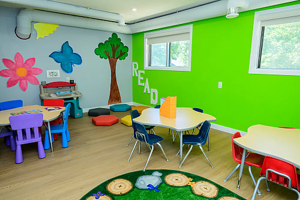 Colorful classroom with child-height tables and a tree mural
